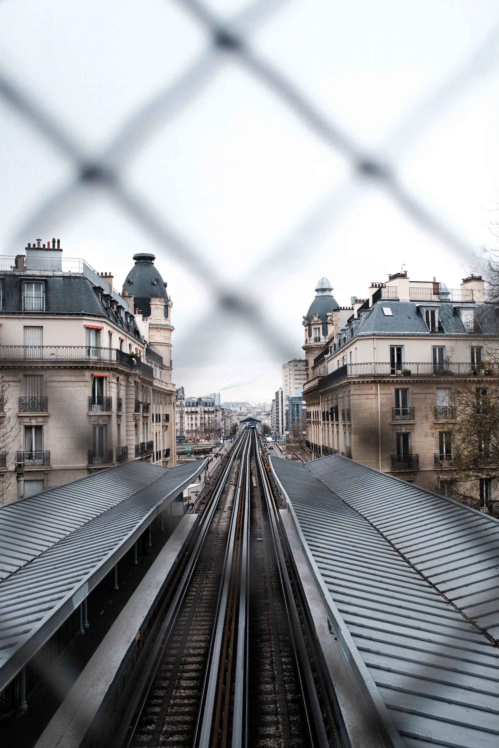 Railway tracks seen through a wire fence.