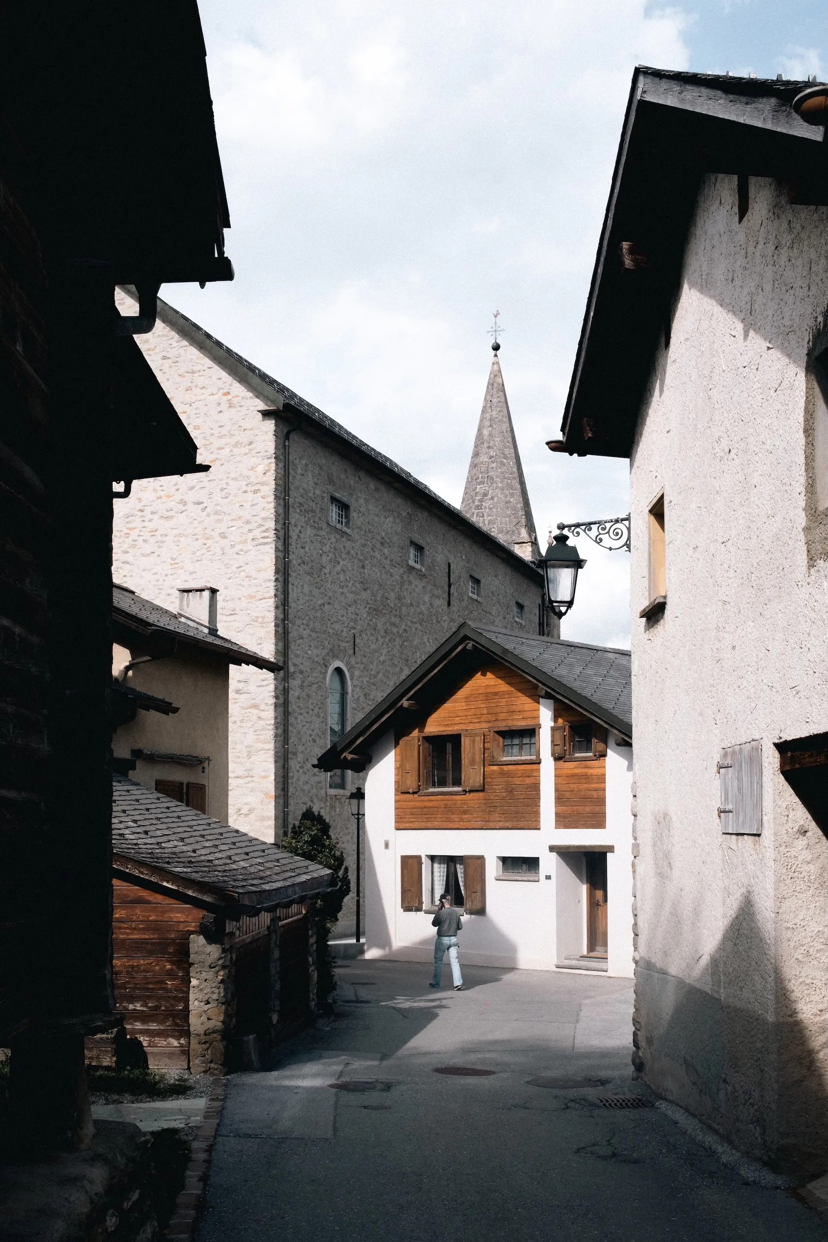 A narrow alley between old houses, a church spire at the end.
