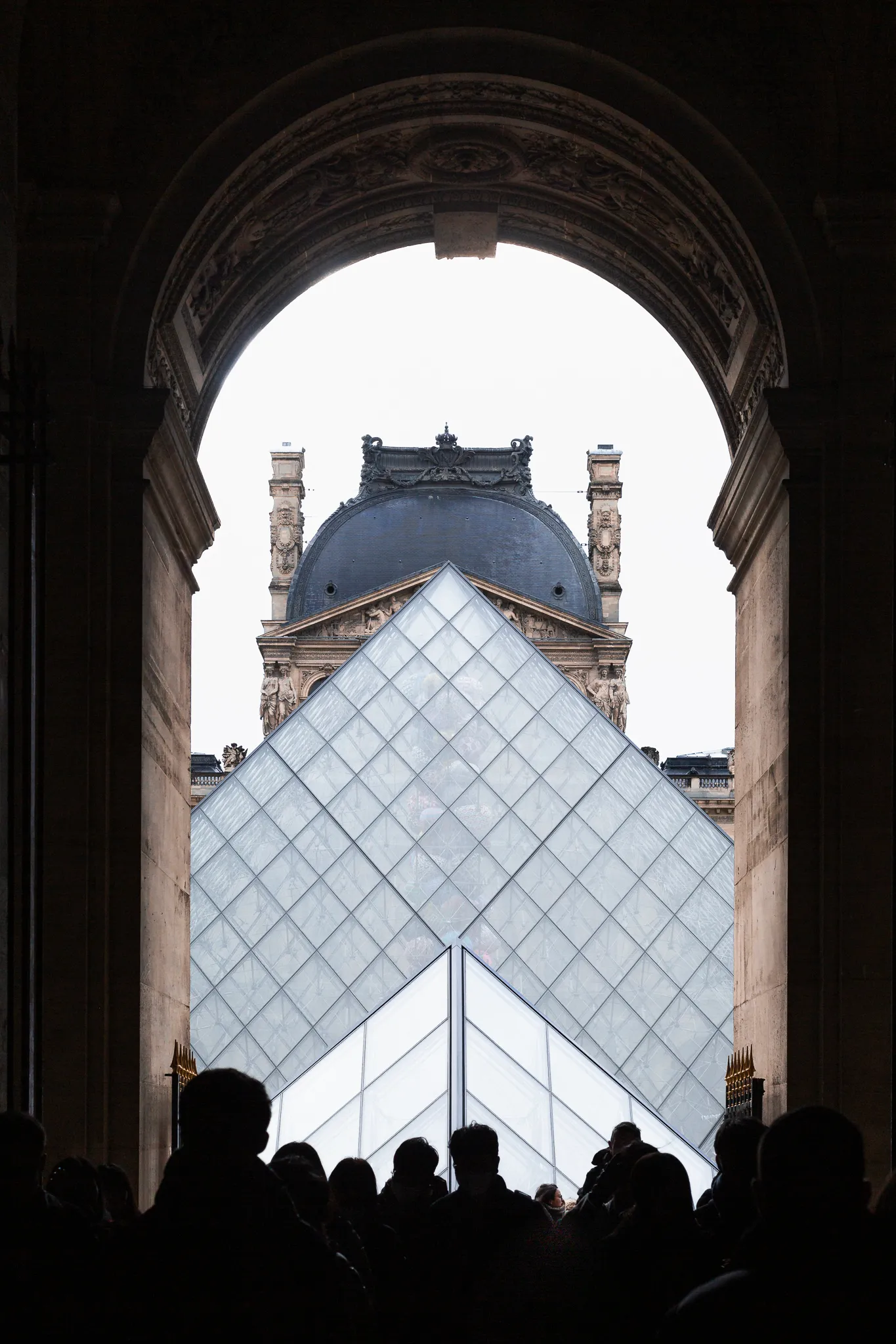 The Louvre pyramid, framed by a dark archway.